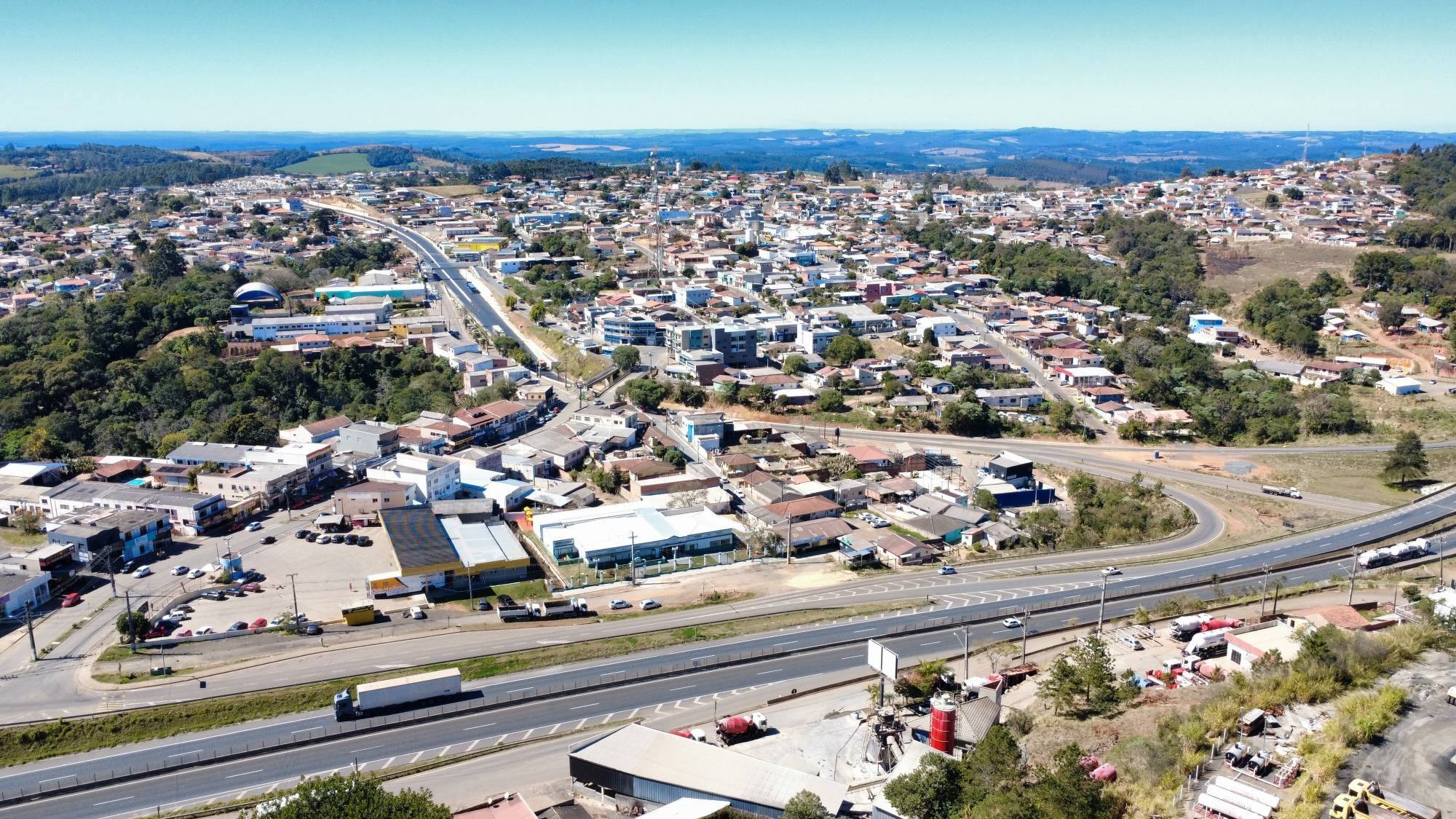 Vista aérea de Imbaú (PR): a rodovia em primeiro plano, o acesso à cidade e a área urbana ao fundo